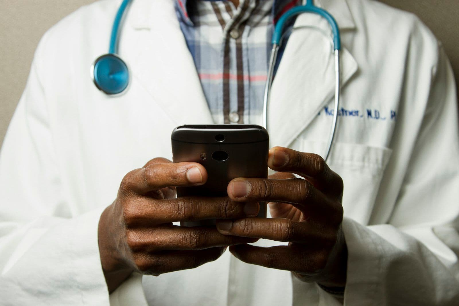 [syncsoft-auto][src:unsplash|id:1576091160399-112ba8d25d1d] Doctor in scrubs writing on clinical clipboard at desk, visualizing healthcare RCM BPO denial-management workflow with AI agents in 2026